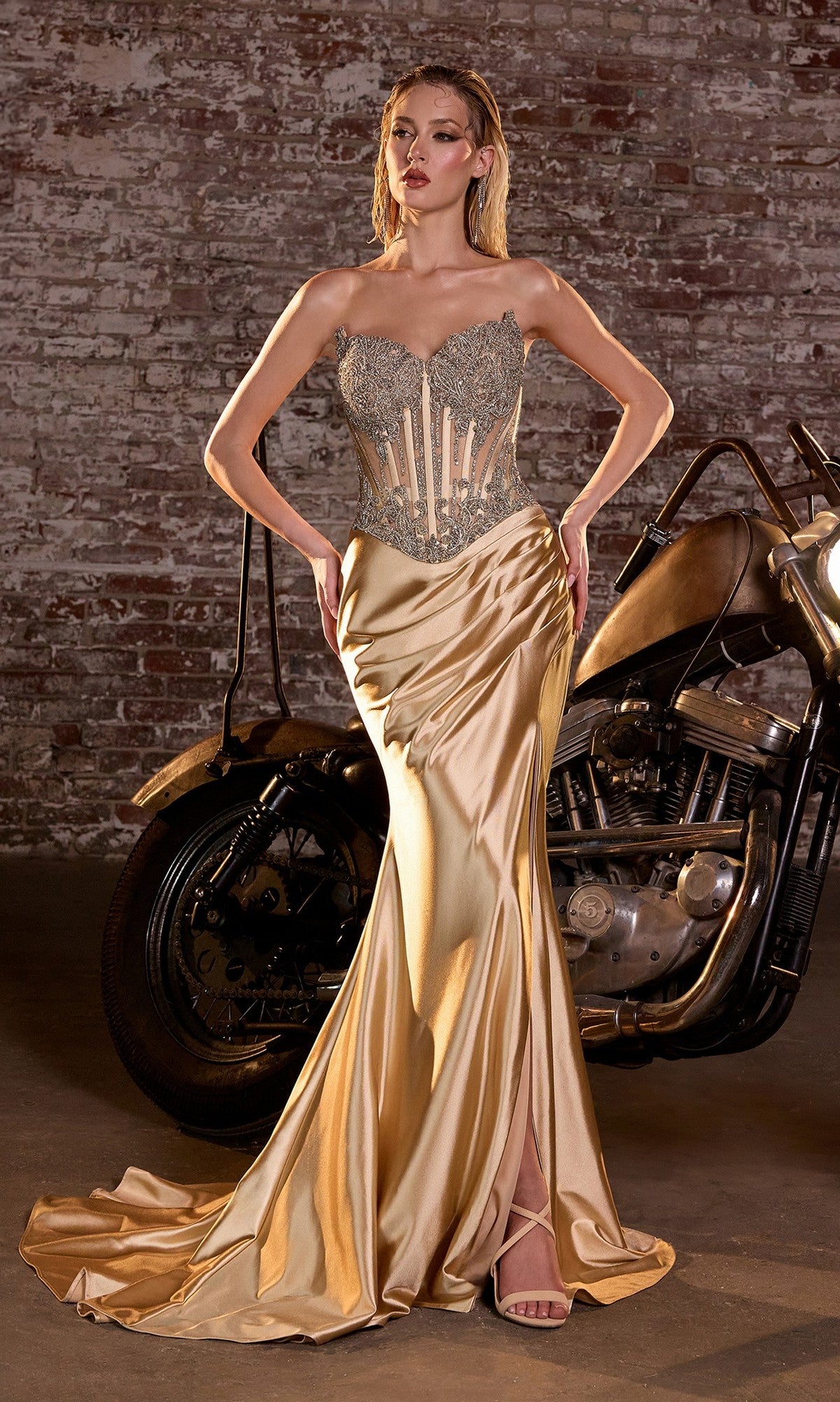 A woman wearing the Ladivine CD736 strapless long corset prom dress stands in front of a vintage motorcycle and a brick wall.